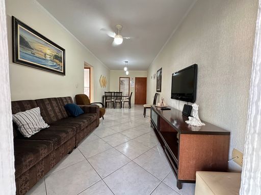 Sala ampla com dois ambientes, excelente iluminação natural, equipada com mesa de jantar para seis pessoas, sofá, rack e TV.