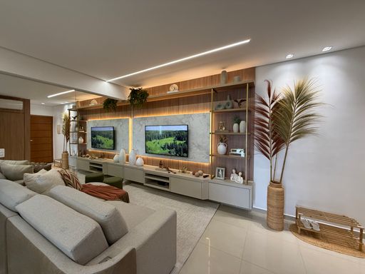 Sala com painel de TV com iluminação em LED, parede espelhada, sofá e ar-condicionado.