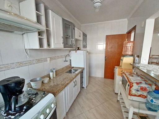 Cozinha americana com armários planejados, fogão, geladeira e ventilador de teto.