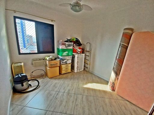 Dormitório com muita iluminação natural, com ar-condicionado de janela e ventilador de teto.