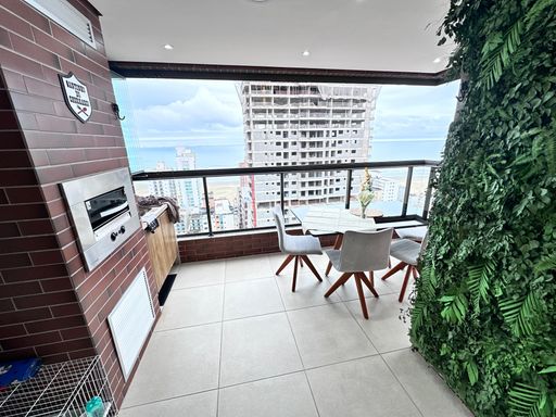 Sacada gourmet envidraçada com vista para o mar.