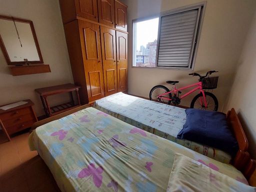 Dormitório espaçoso com duas camas de solteira, um beliche e guarda-roupa.