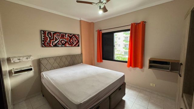 Suíte com uma cama de casal, guarda-roupa e ventilador de teto.