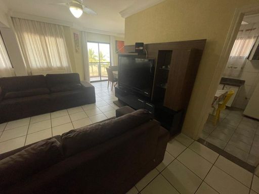 Sala ampla de dois ambientes com três sofás e ventilador de teto.
