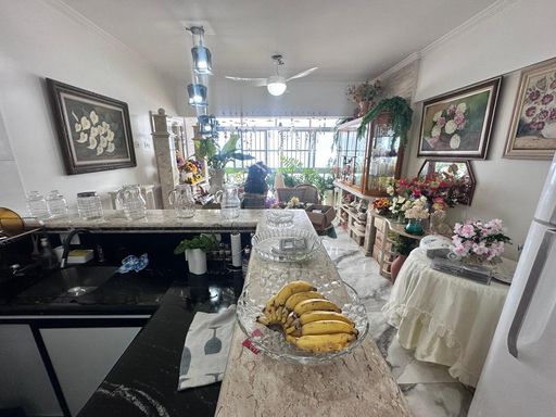 Sala bem iluminada com ventilador de teto e cozinha americana.