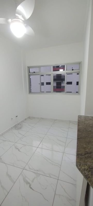 Sala com piso reformado com ventilador de teto e uma janela grande.