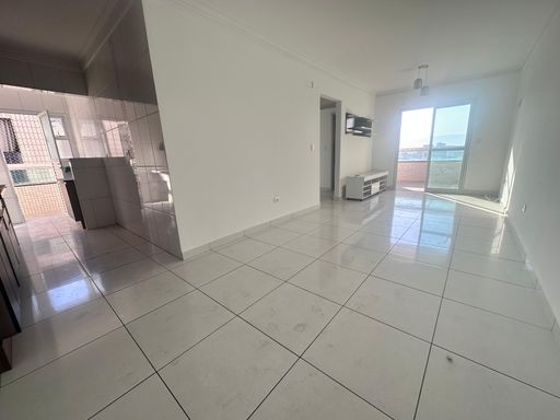 Sala de 2 ambientes com painel de TV, paredes brancas e acesso a sacada gourmet.