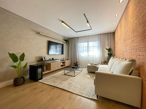 Sala espaçosa, muito bem iluminada, com sofá e piso laminado.