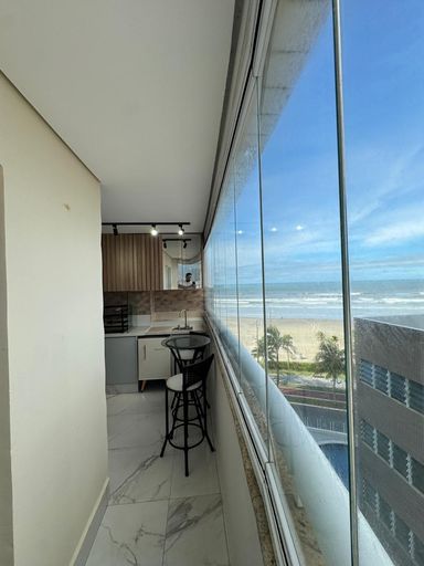 Sacada gourmet envidraçada com vista para o mar.