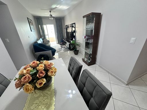 Sala de 2 ambientes com mesa de jantar, sofá, ventilador de teto e acesso a sacada gourmet.