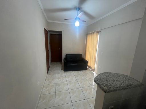 Sala bem iluminada com sofá cama e ventilador de teto.
