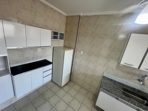 Cozinha com armários brancos e ventilador de teto.
