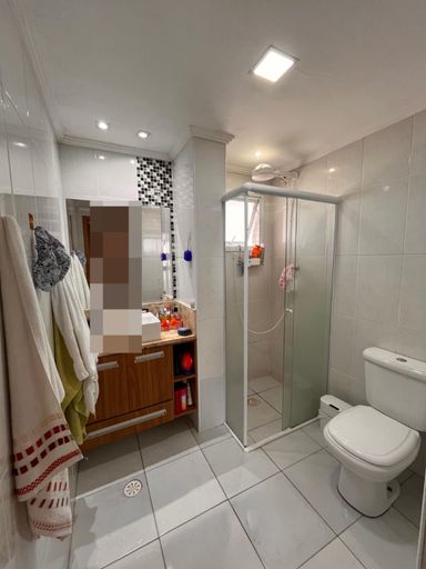 WC suíte com box de vidro, pia, gabinete e espelho.