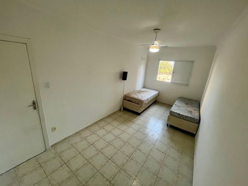 Dormitório espaçoso com muita iluminação natural com duas camas de solteiro e ventilador de teto.