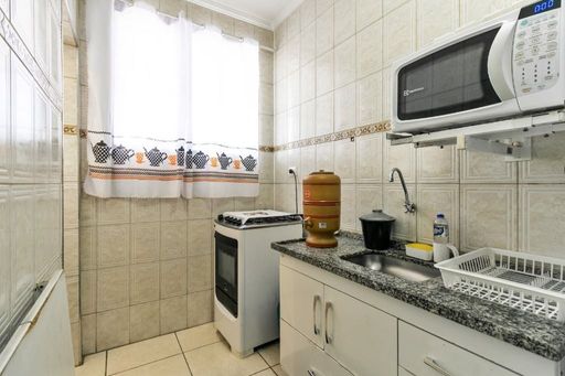 Cozinha com armários brancos, geladeira, pia com gabinete e fogão.