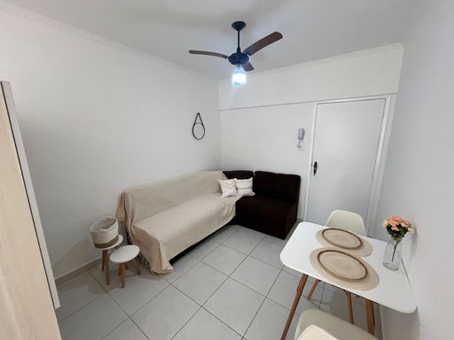 Sala living mobiliada e bem iluminada com um sofá, mesa e ventilador de teto.