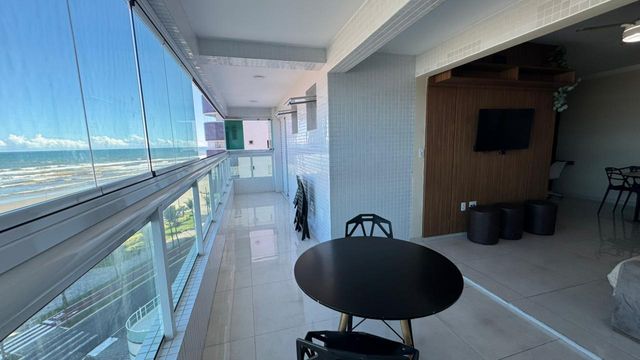 Sacada gourmet envidraçada com vista para o mar.