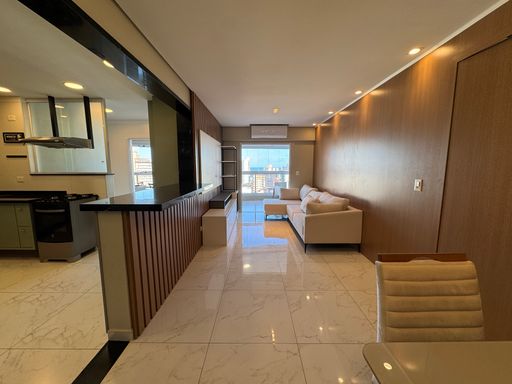 Sala de dois ambientes com nichos na parede, ar-condicionado, sofá e acesso à sacada gourmet.