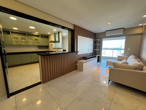 Sala de dois ambientes com nichos na parede, ar-condicionado, sofá e acesso à sacada gourmet.