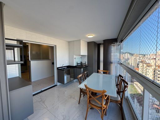 Sacada gourmet envidraçada com vista para o mar.