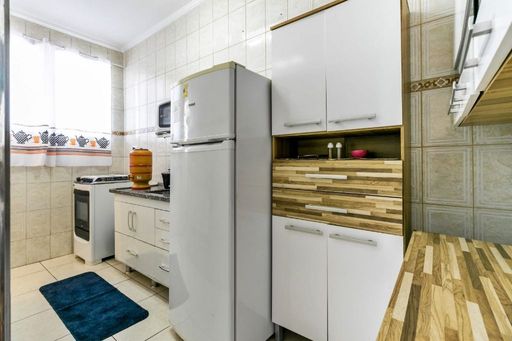 Cozinha com armários brancos, geladeira, pia com gabinete e fogão.