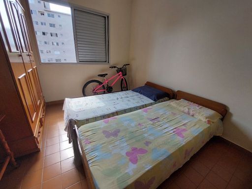 Dormitório espaçoso com duas camas de solteira, um beliche e guarda-roupa.