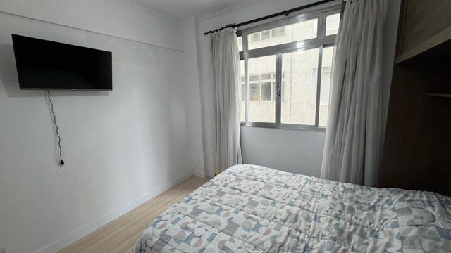 Dormitório bem iluminado e com uma cama de casal.