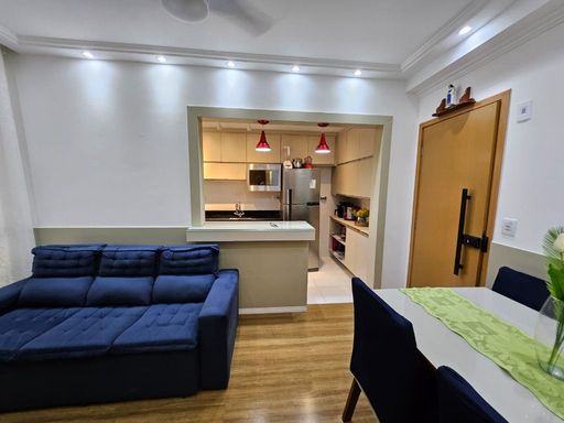 Sala de 2 ambientes com um sofá, painel de TV e mesa de jantar.