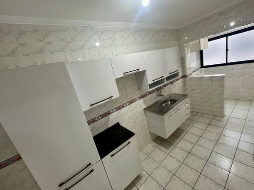 Cozinha com armários brancos e pia e gabinete.