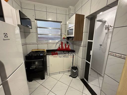 Cozinha americana com armários, fogão, pia e gabinete.