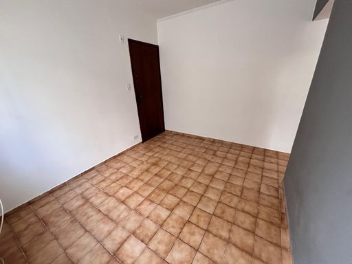 Sala bem iluminada com uma janela grande e parede cinza.