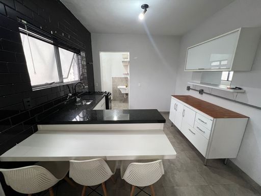 Cozinha americana muito bem iluminada com armários.