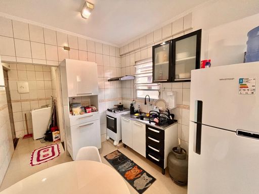 Cozinha com uma pia, geladeira, armários e mesa de jantar.