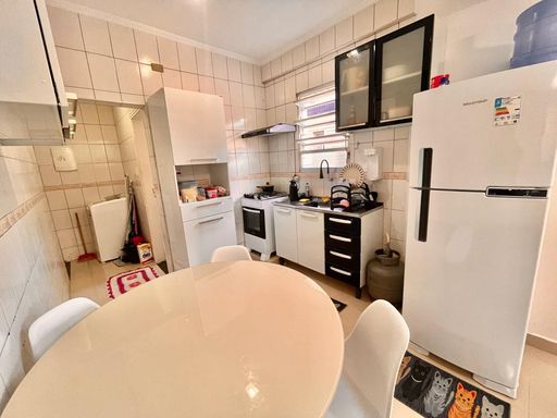Cozinha com uma pia, geladeira, armários e mesa de jantar.