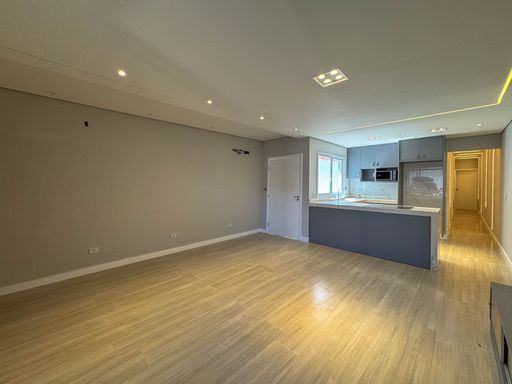Sala ampla de dois ambientes com teto rebaixado em gesso com iluminação em LED e painel de TV.
