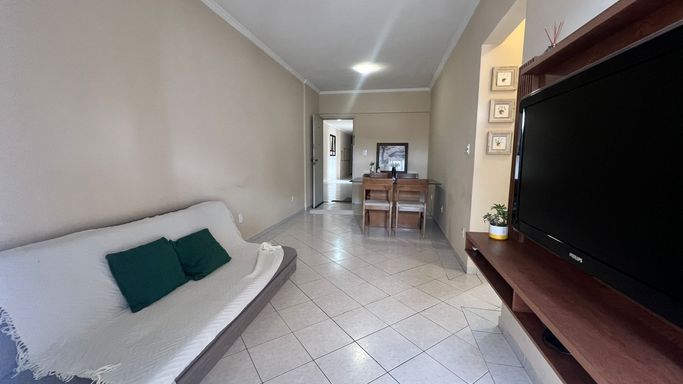 Sala de 2 ambientes com sofá, painel de TV e mesa de jantar.