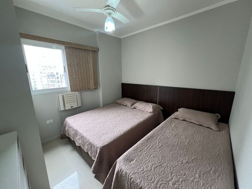 Suíte com cama de casal, cama de solteiro, armários planejados, ventilador de teto e ar-condicionado de parede.