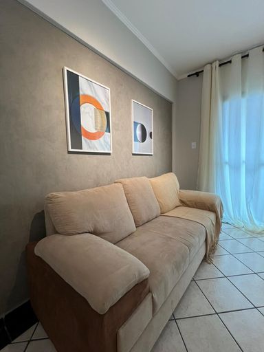 Sala ampla e bem iluminada com um sofá e painel de TV.