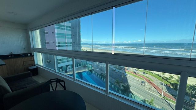 Sacada gourmet envidraçada com vista para o mar.