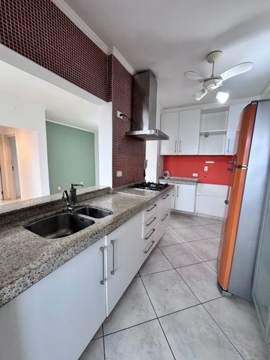 Cozinha americana com armários planejados e uma geladeira.