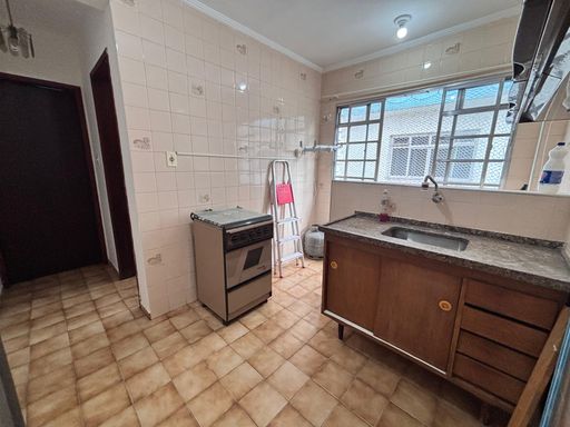 Cozinha bem iluminada com uma pia, gabinete e fogão.