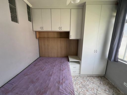 Dormitório planejado com uma cama de casal com uma janela com vista para o mar.