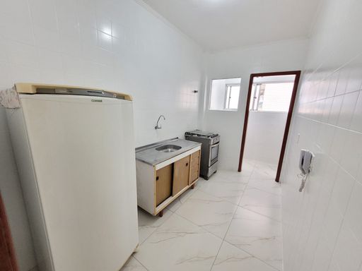 Cozinha com pia, gabinete, fogão, geladeira e piso em porcelanato.