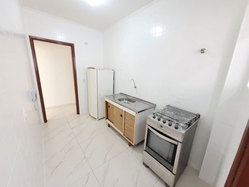 Cozinha com pia, gabinete, fogão, geladeira e piso em porcelanato.