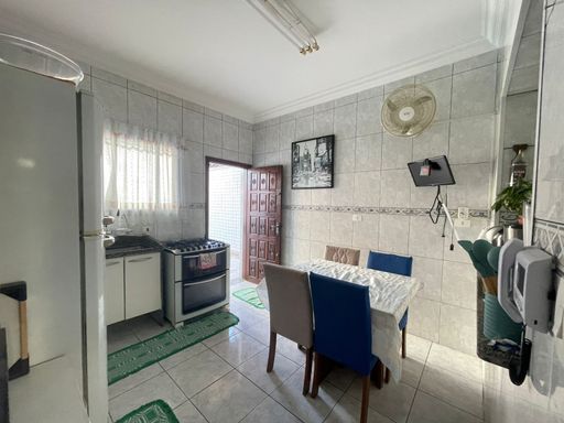 Cozinha americana com mesa para quatro pessoas, armários planejados e fogão.