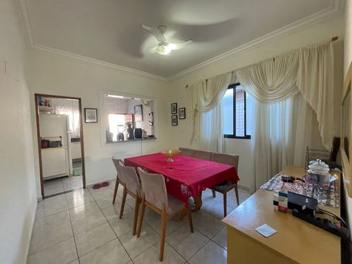 Sala de jantar com mesa para quatro pessoas e ventilador de teto.