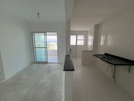 Sala bem iluminada e cozinha americana.