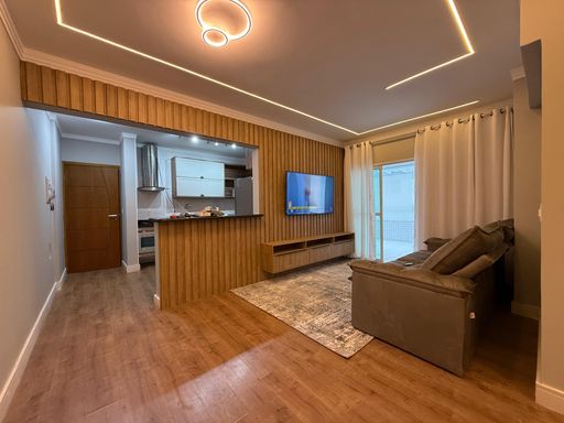 Sala de dois ambientes com sofá, mesa de jantar, TV e ar-condicionado.
