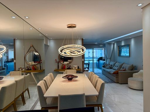 Sala ampla de 2 ambientes com uma parede espelhada e  mesa de jantar.