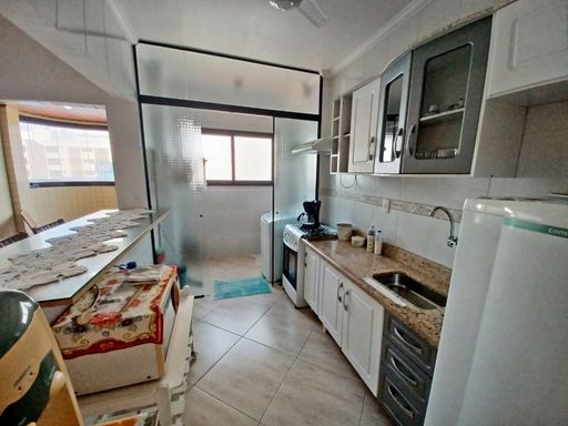 Cozinha americana com armários planejados, fogão, geladeira e ventilador de teto.